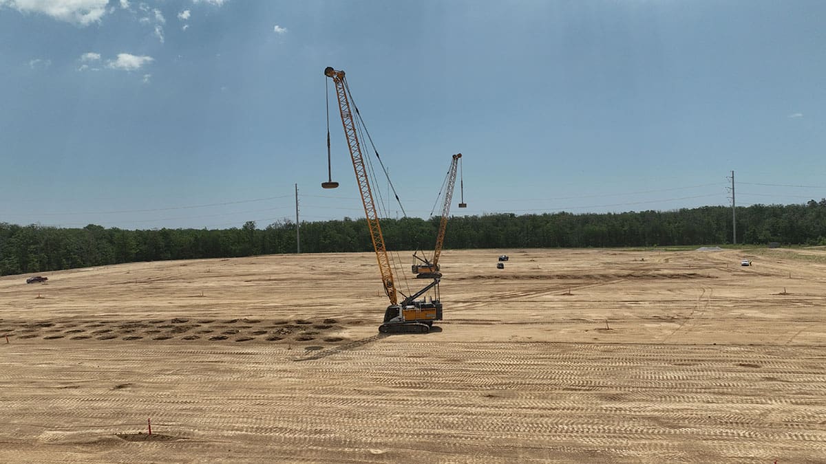 Heavy machinery performing dynamic compaction on a construction site to improve soil stability