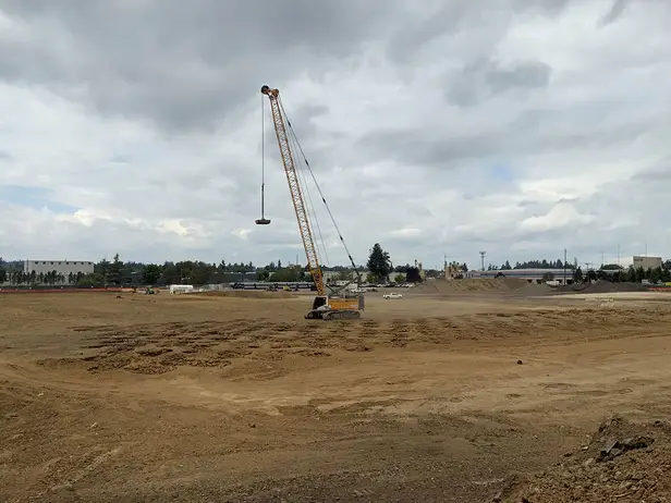 Liebherr crane performing dynamic compaction at a construction site in Oregon, with impact zones visible on the compacted soil surface.