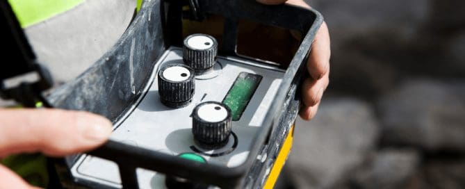 Construction worker holding a vibration monitoring control panel to ensure construction safety and compliance.