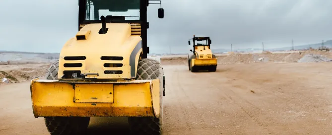 Two Vibratory Soil Compactors on construction site. Industrial roadworks at highway with heavy-duty machinery