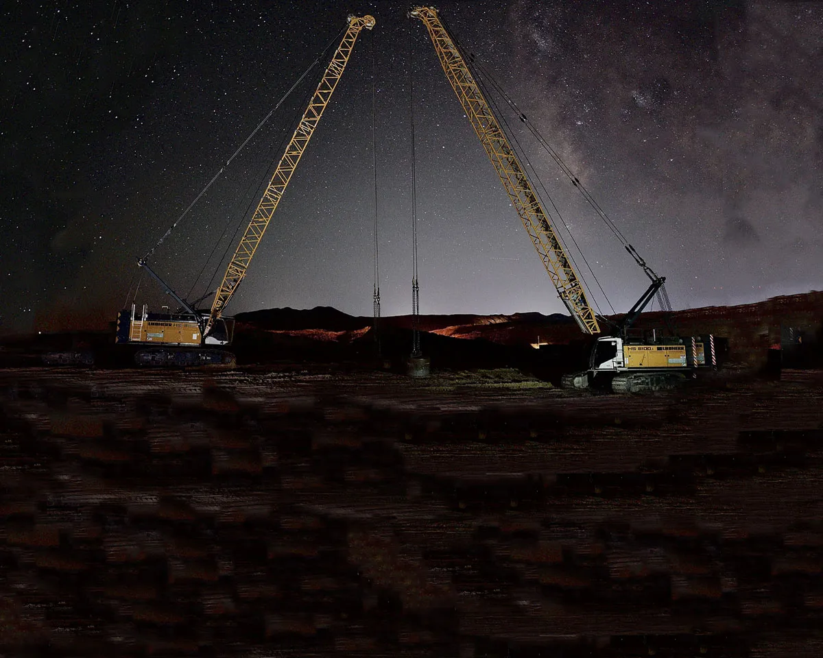 Libherr cranes at work on a construction site in the United States under a beautiful starry night sky.