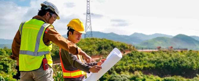 Engineer head point to the planer paper and discuss with his team for the construction near the forest with copy space in image.