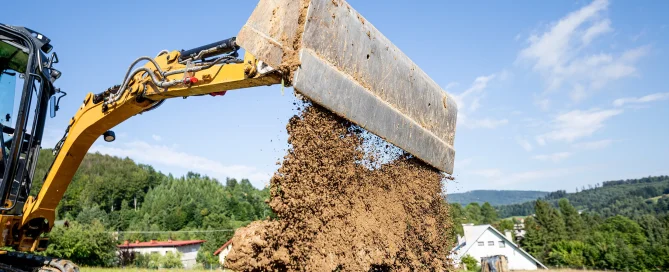 Excavator placing and compacting soil during ground improvement, illustrating how deep dynamic compaction strengthens weak soils for stable foundations.