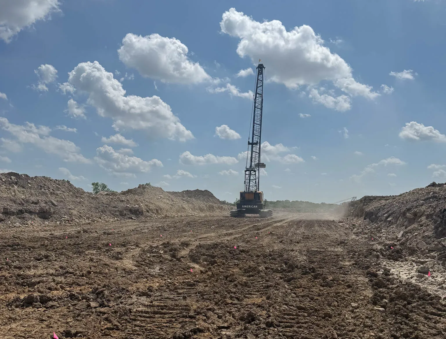 crane-in-earthwork-cut-fort-worth-densification. American lattice-boom crane at the end of a rutted earthwork cut on a Fort Worth ground improvement site