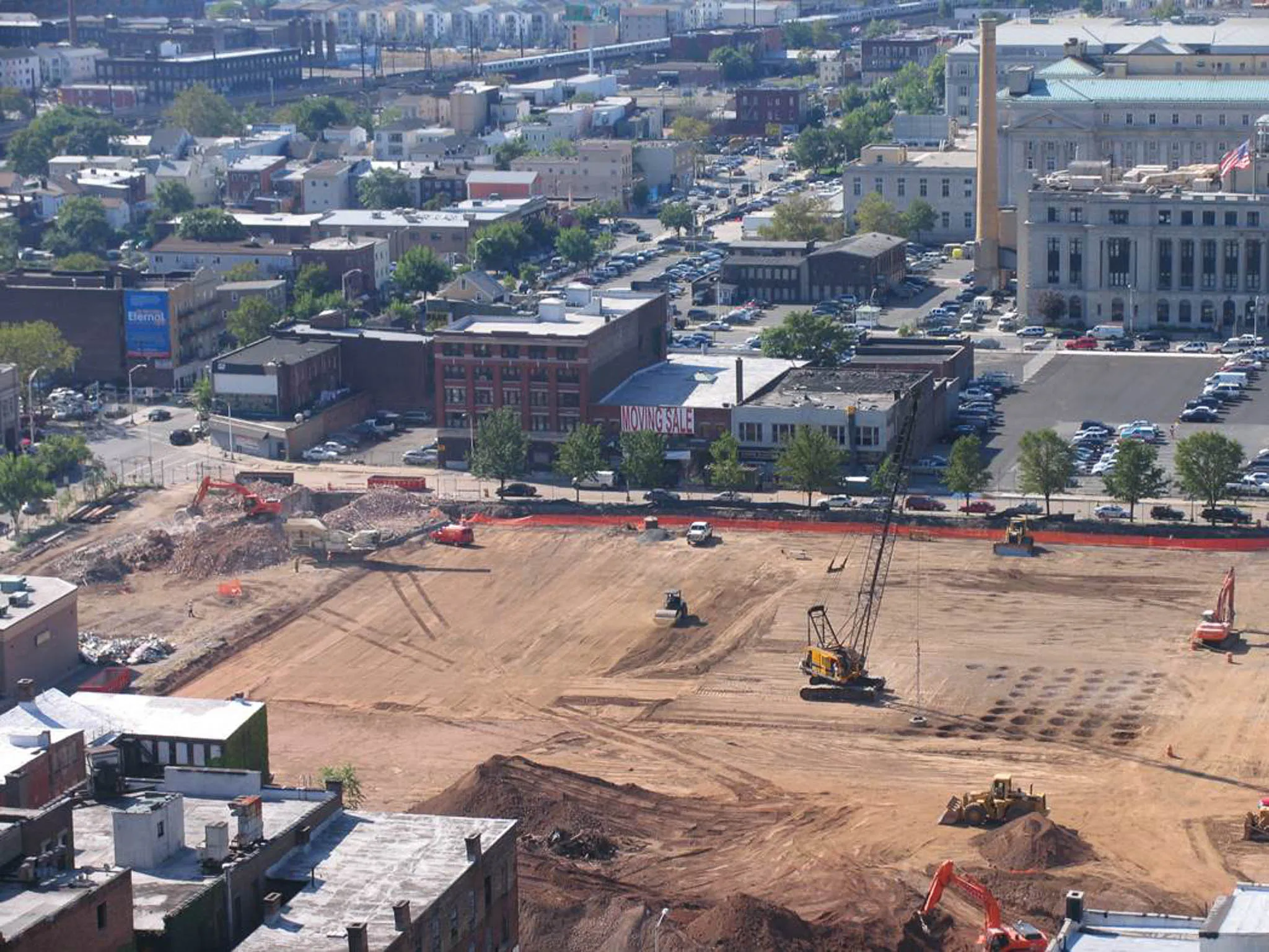 urban-redevelopment-compaction-aerial-newark-densification. Aerial view of a downtown Newark redevelopment site with a lattice crane working a dynamic compaction grid