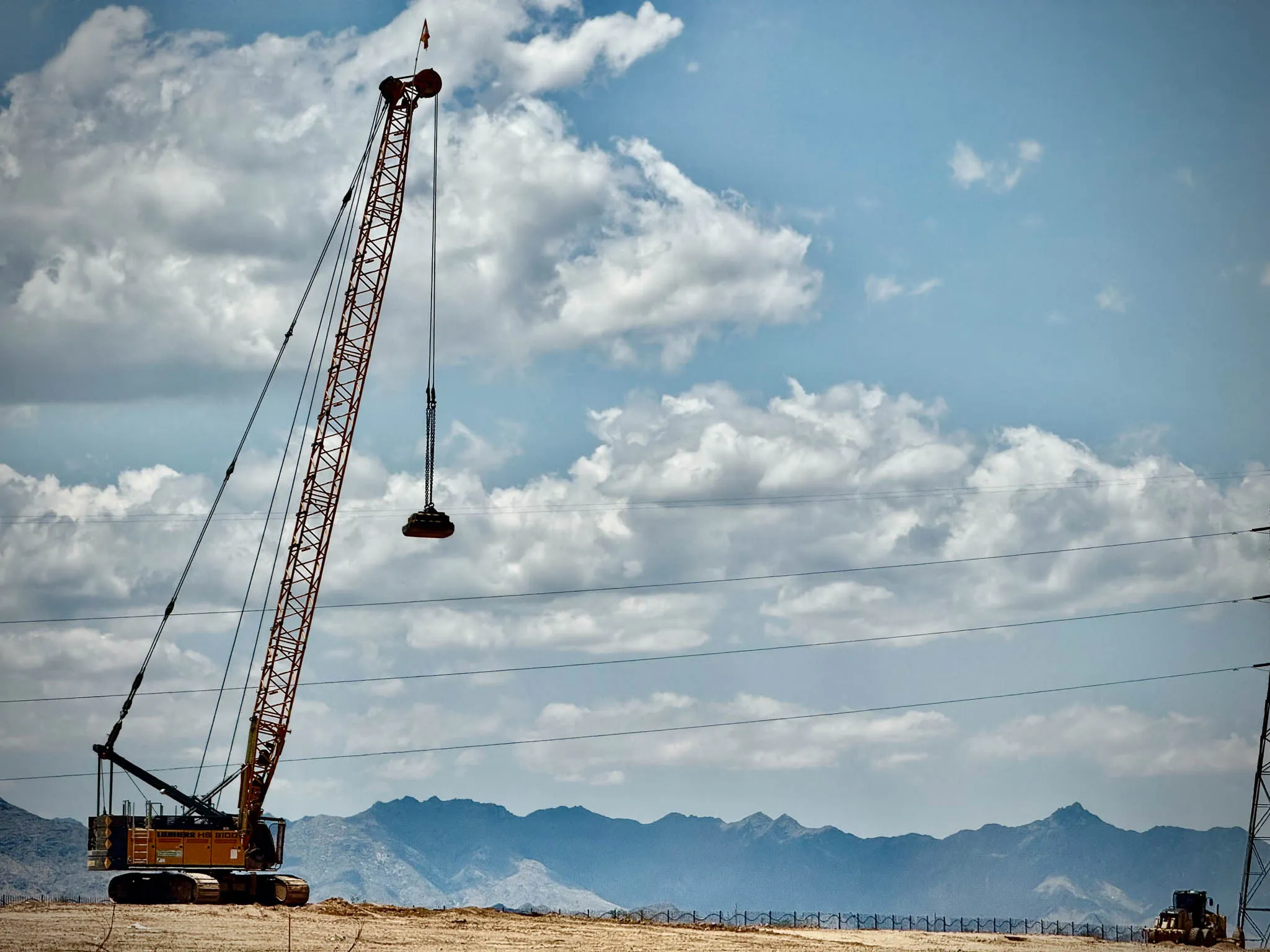 crawler-crane-lifting-tamper-vernal-utah-densification. Liebherr HS 8100 crawler crane lifting a compaction weight above a desert site in Vernal, Utah